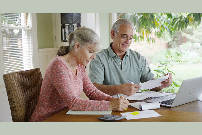 Senior couple paying bills together on laptop